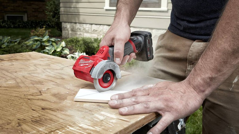 Person using a Milwaukee cutoff tool on wood