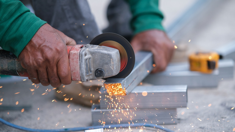 Person using a cut off tool on metal beam