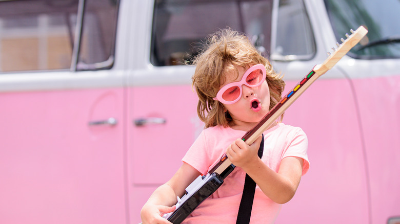 Child playing toy guitar outside