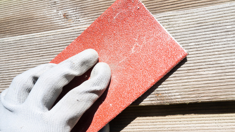 A person using sandpaper on wood