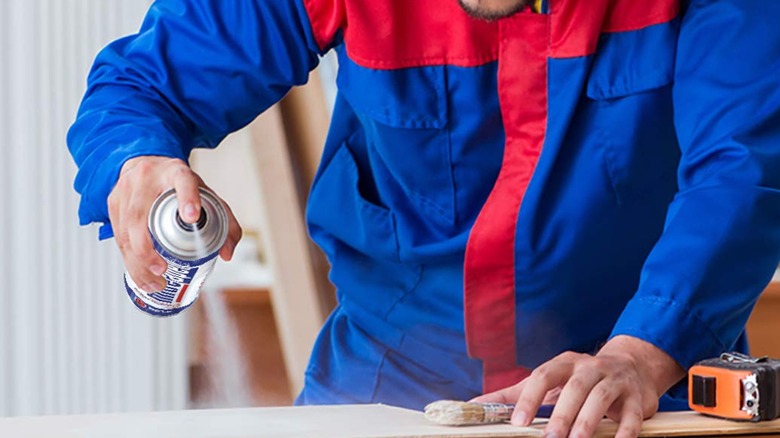 A person spraying an activator spray for superglue