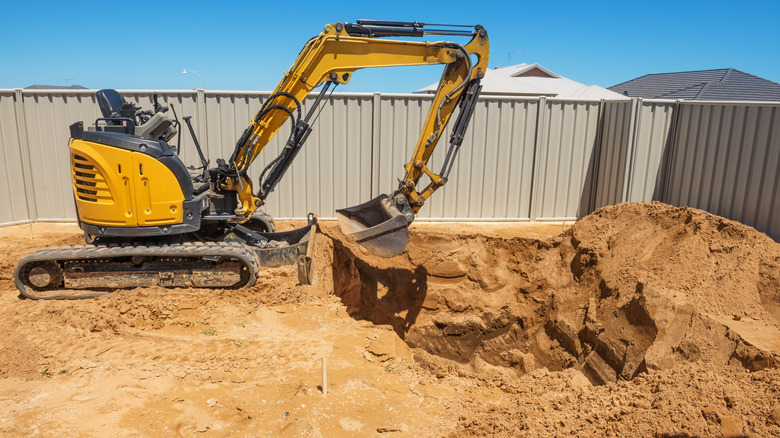 excavator digging hole in backyard