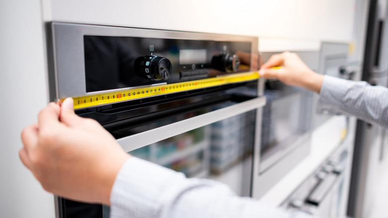 person measuring oven length