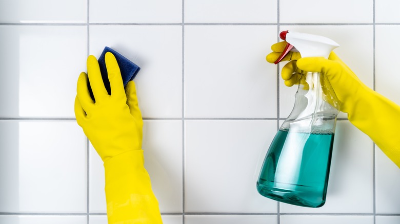 cleaning tile with yellow gloves