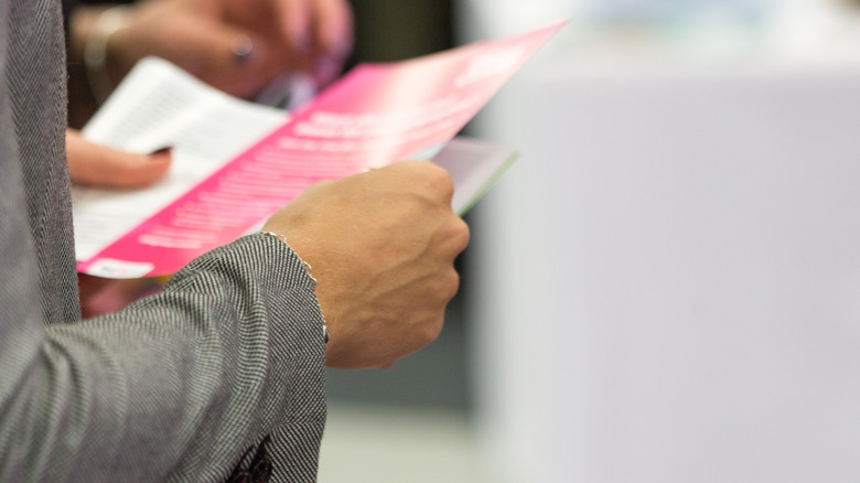 hands holding a pink pamphlet