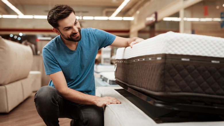 person touching mattress in the store