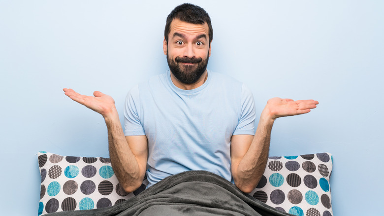 man sitting in bed with pillow