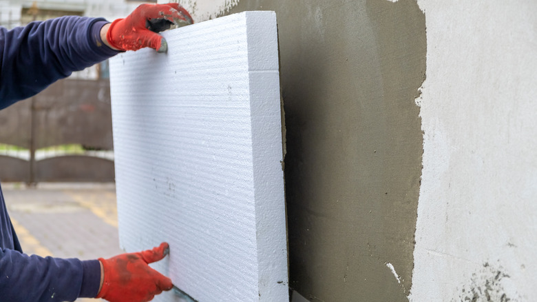 gloved hands placing insulation