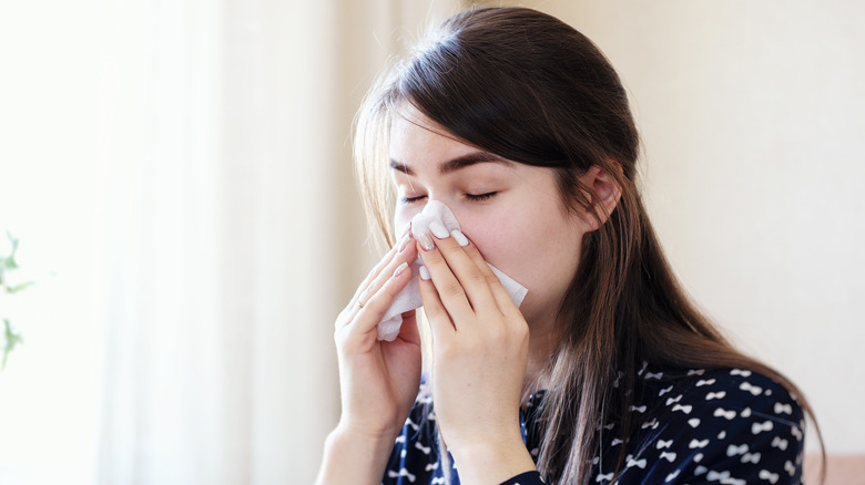 woman blowing nose from allergies