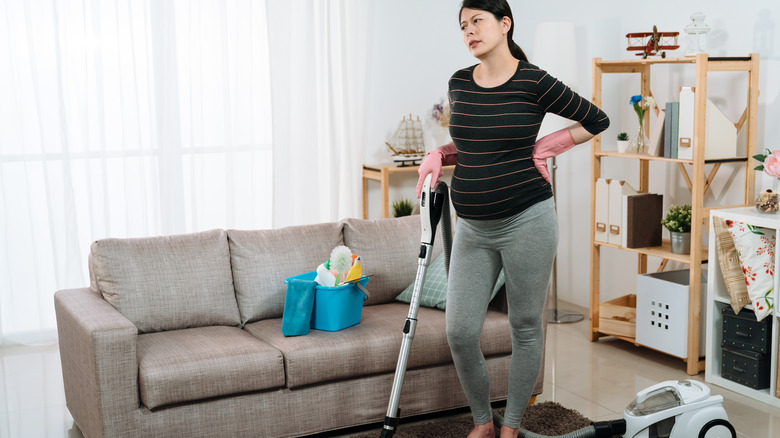 pregnant woman with back pain vacuuming