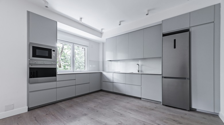 A bare kitchen with appliances, white walls, and gray kitchen cabinets and casework