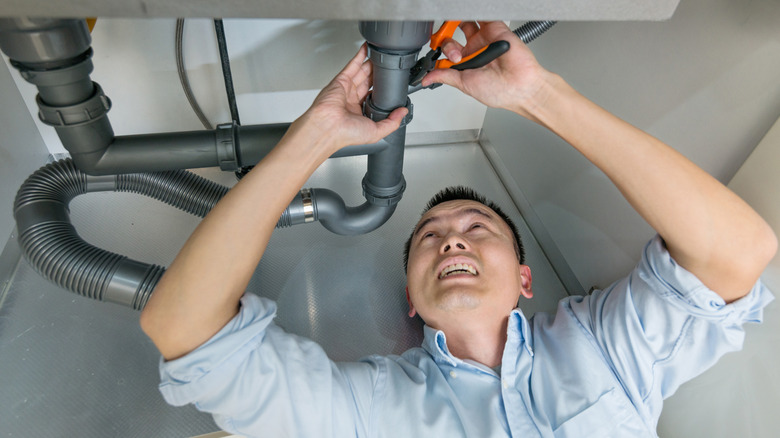 A man checking pipes under the sink