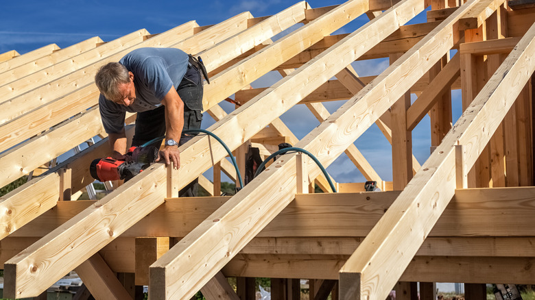 man nailing roof of home