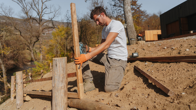 A person building a fence in the dirt