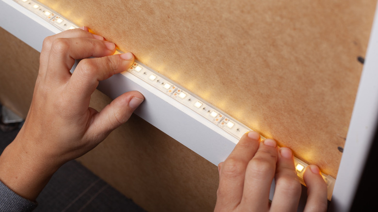 Hands holding an LED light strip in place