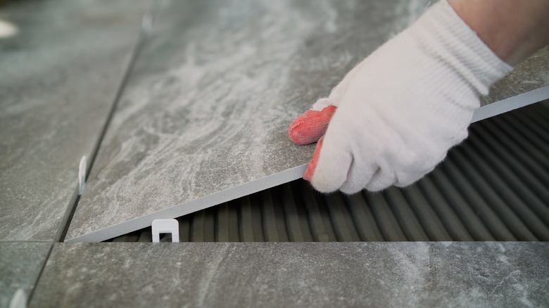 A person lays tiles on a bathroom floor