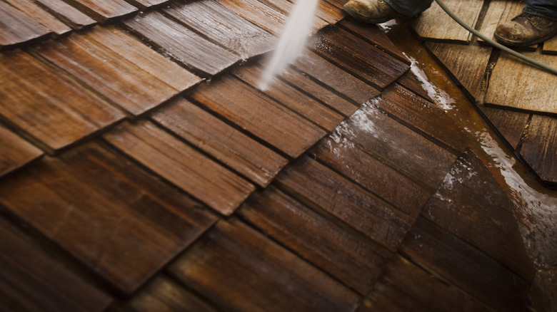 Person pressure washing wood shingles