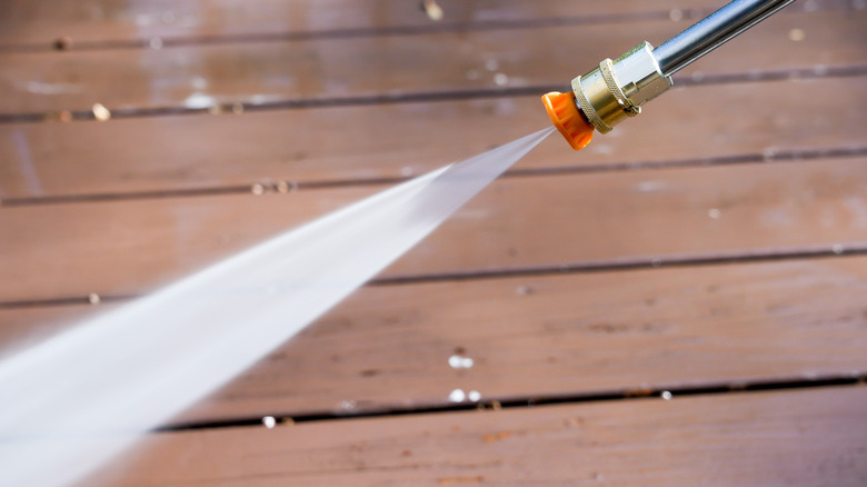 Person using a yellow nozzle on a pressure washer