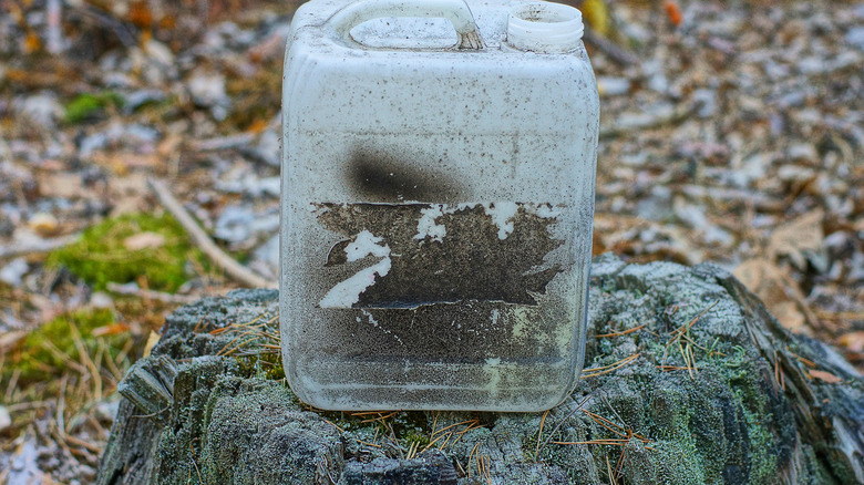 Dirty white chemical bottle on an old tree stump