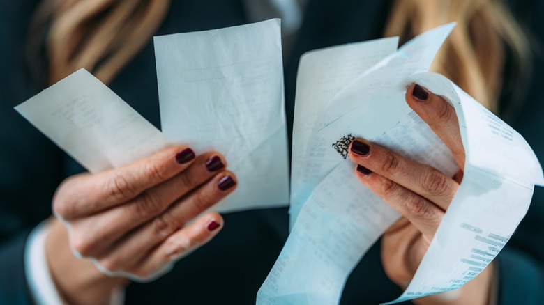 person holding several receipts 