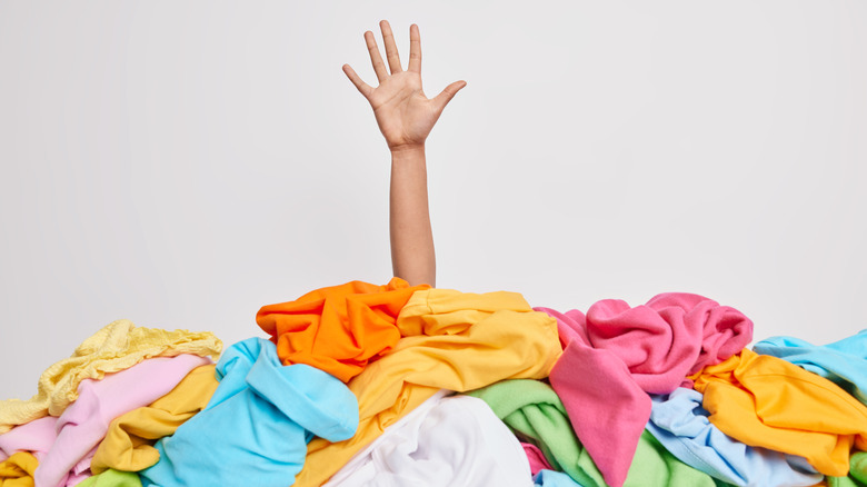 hand reaching out of clothes pile