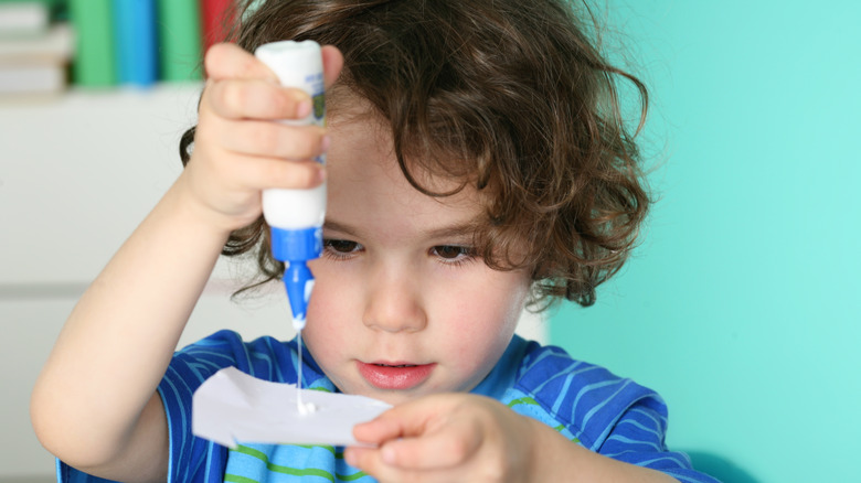 A child squeezing glue onto paper