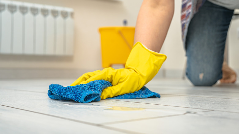 Wiping spill on white floor with blue microfiber cloth