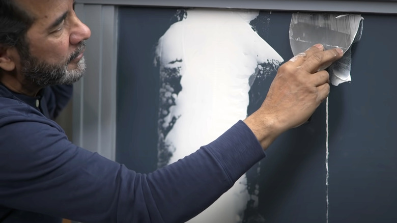 man repairing navy blue wall