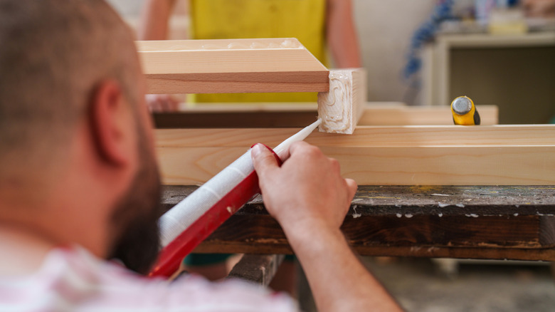 A man applying wood glue to the base of a two by four