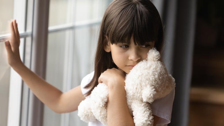 little girl with bear by window