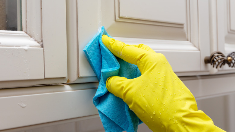 Gloved hand cleaning cabinets