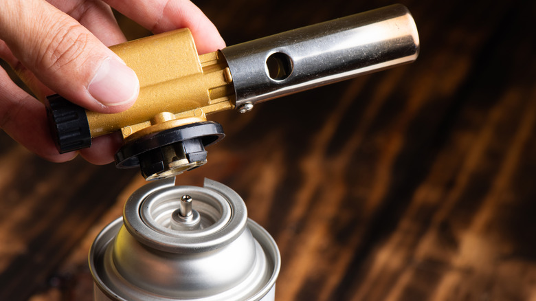 Man attaching nozzle to handheld propane tank.