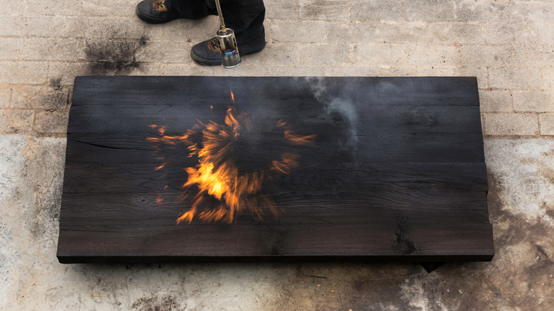 A man practicing Yakisugi technique on a piece of wood.