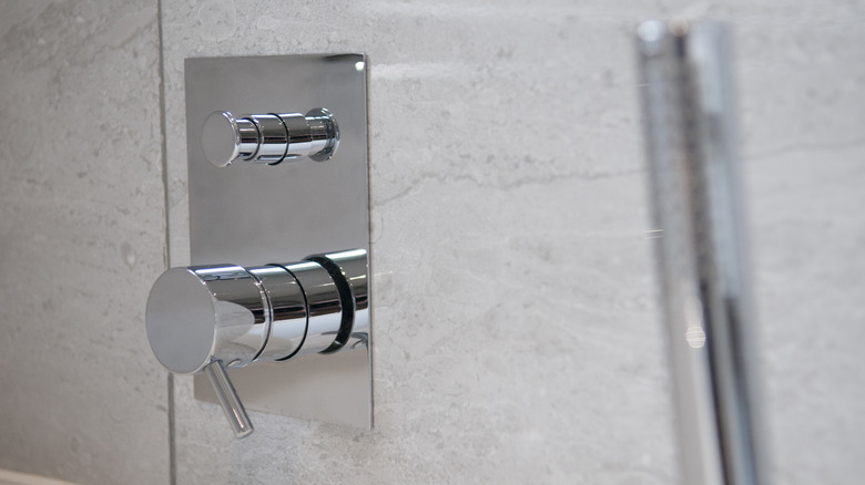 Chrome shower handle against shower tiles.