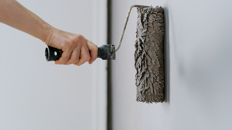 Person using a textured roller on a wall