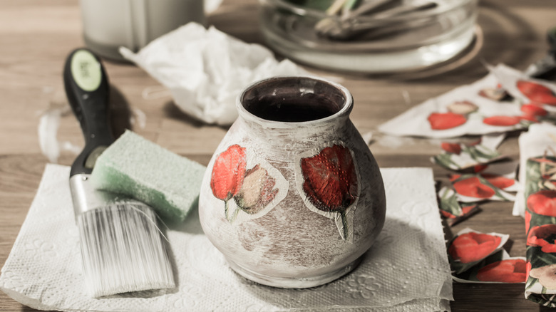 Decoupaged vase on table with supplies