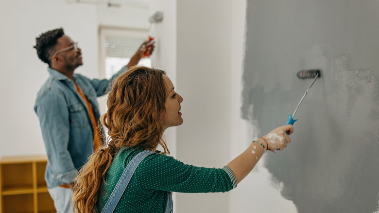 two people painting walls gray