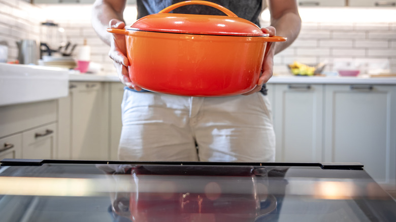 Man holding vibrant orange enameled cast iron dutch oven