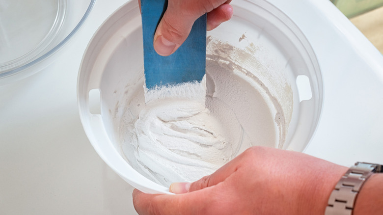 A hand mixing white grout