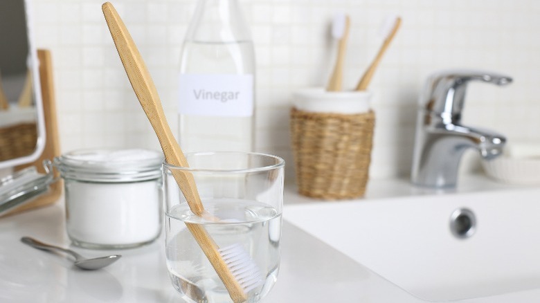 brush dipped in glass with solution with vinegar and baking soda on background