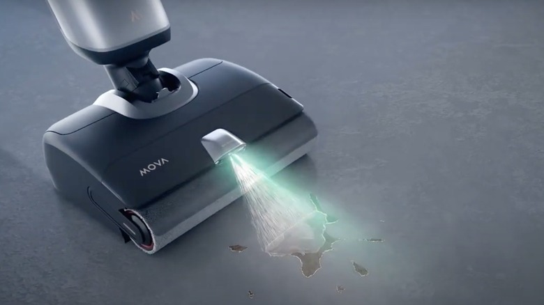 Black and silver MOVA X4 Pro vacuum spraying water onto stain on floor