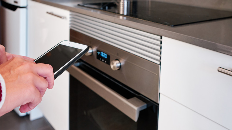 A person controlling their oven with their smart phone