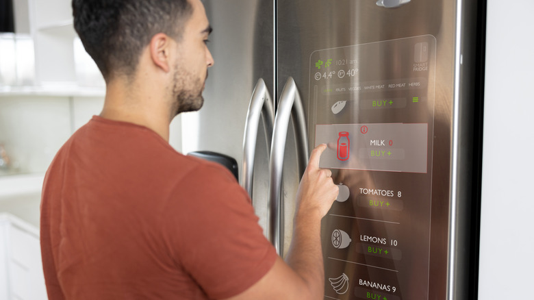 A person using a touchscreen refrigerator