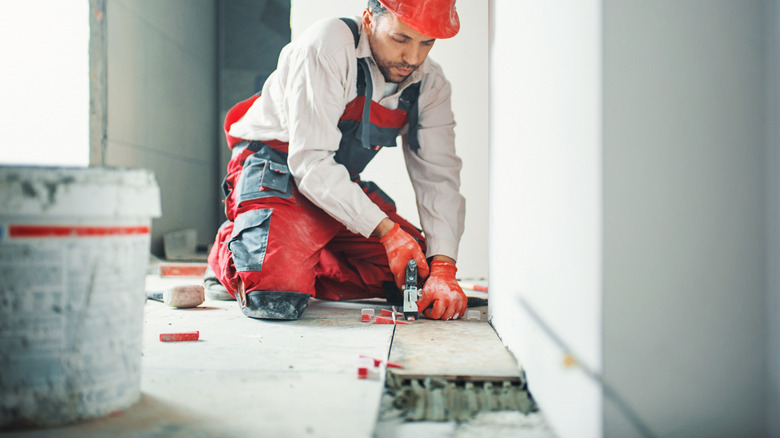 Man laying floor tile next to wall