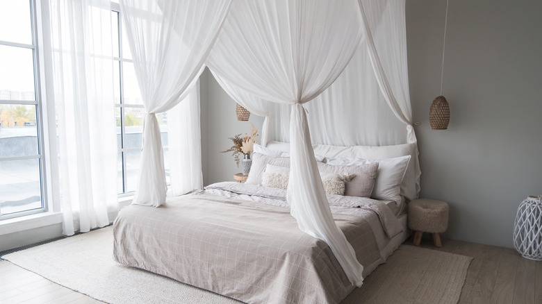 Canopy bed sitting by a window in a bedroom