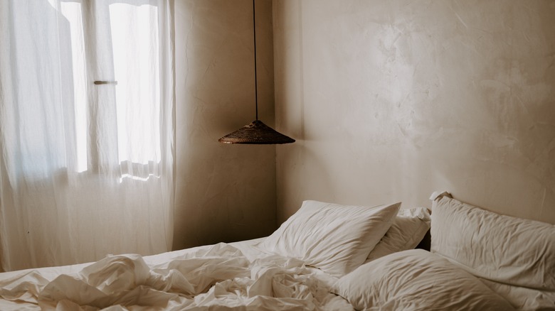 limewashed bedroom with brown sheets