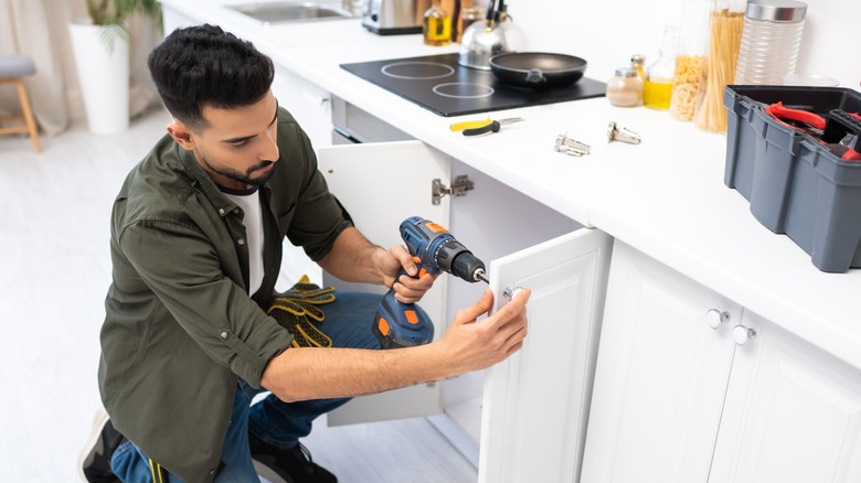 person adding cabinet hardware