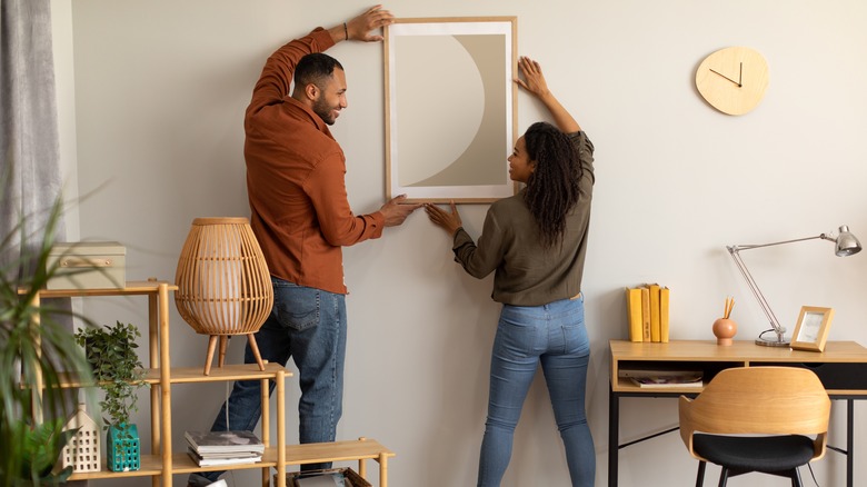 couple hanging framed artwork together