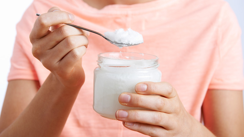 person holding jar of coconut oil