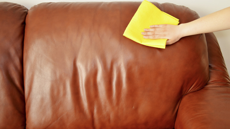 Wiping down a brown leather sofa